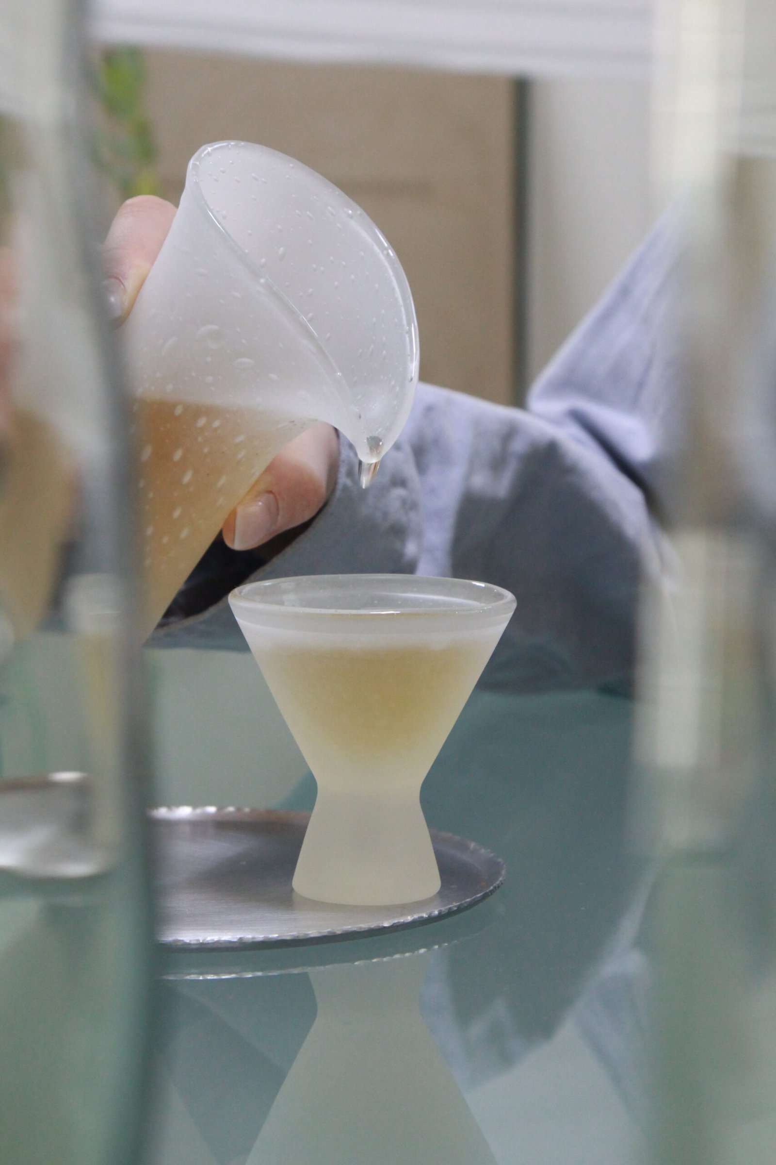 Tea being poured into a handcrafted glass cup by Multeo during a quiet tea ritual.